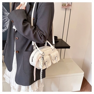 Vue détaillée du sac blanc en cuir ciré avec plusieurs poches et pendentifs en corde