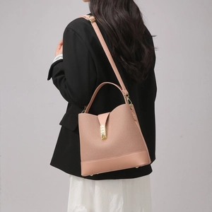 Detail view of pink bucket bag with woven texture and gold clasp on a model