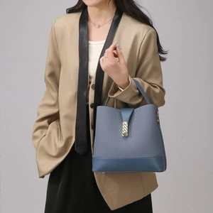Detail of blue-gray bucket bag with leather-woven texture and gold metal clasp closure