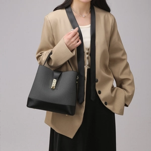 Detail of grey knitted bucket bag with black leather base and gold metal clasp on model