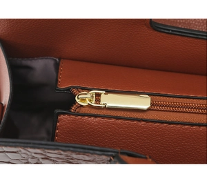 Makroaufnahme von goldenem Reißverschluss und Leder mit Krokodilprägung an der Tasche