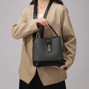 Detail of contrast bucket bag featuring grey woven texture and black leather handle