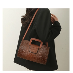 Detail der braunen Krokodilmuster-Handtasche mit Hohlgriff und Schultergurt