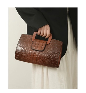 Nahaufnahme der braunen Handtasche mit Krokodilprägung, Umschlagklappe und Griff