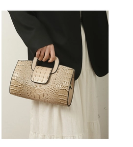 Detail der beigefarbenen Handtasche mit Kroko-Prägung und strukturiertem Tragegriff