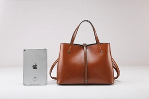 Close-up of brown oiled leather tote bag with iPad for size reference and long strap