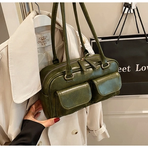 Detail of dark green vintage oil wax leather bag with double front pockets and gold zippers