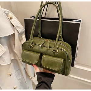 Close-up of olive green vintage handbag showing dual front pockets and glossy PU texture