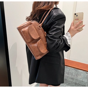 Detail of vintage brown PU leather shoulder bag featuring dual front flap pockets