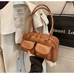 Detail of vintage brown textured leather handbag with front flap pockets and long handles