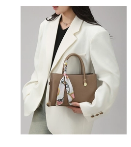 Brown lychee leather tote bag with decorative silk scarf on handle worn with white blazer