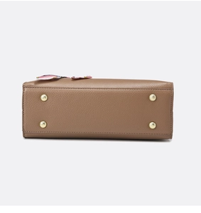 Detail view of brown pebbled leather bag bottom with four protective gold metal feet