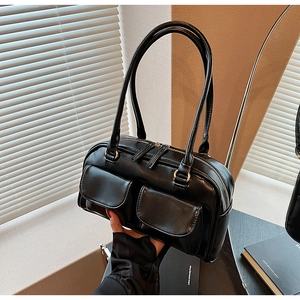 Detail of black faux leather shoulder bag featuring double front pockets and gold zippers