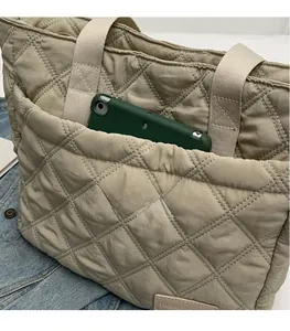 Close-up of beige quilted tote bag showing large front pocket and rhombus stitching pattern
