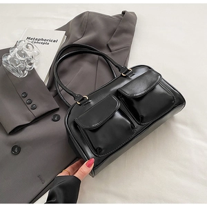 Detail of black glossy handbag featuring double front flap pockets and retro design