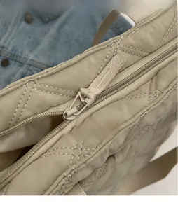 Detailed view of the smooth nylon zipper and quilted diamond pattern on the beige handbag