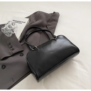 Close-up of black faux leather handbag texture with gold metal buckles and slim straps