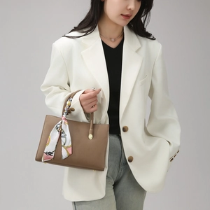 Close-up of brown lychee leather tote bag featuring a decorative printed silk scarf on handle