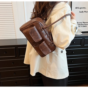 Detail of brown retro shoulder bag with twin flap pockets and textured faux leather