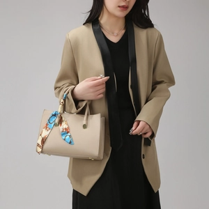 Detail of beige lychee leather tote bag featuring an elegant floral silk scarf wrapped handle