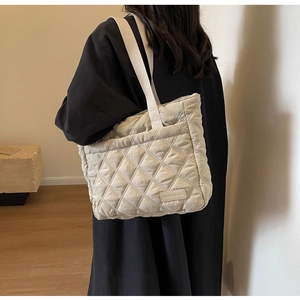 Detail of beige quilted shoulder bag featuring elegant diamond lattice and leather logo label