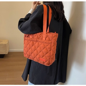 Detail of orange quilted tote bag in padded fabric with wide shoulder straps