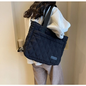 Detail of black quilted shoulder bag with diamond stitching and fashion label