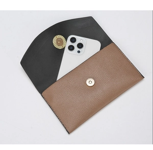 Detailed view of bicolor envelope clutch showing inner capacity with a smartphone