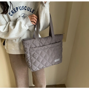 Close-up of quilted grey-purple crossbody bag with minimalist diamond stitching detail