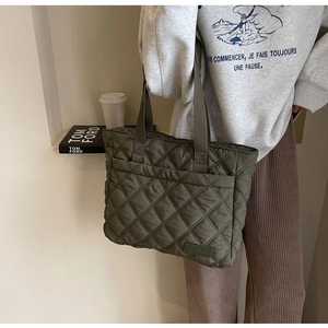 Detailed close-up of quilted olive green tote bag with premium satin texture and branding