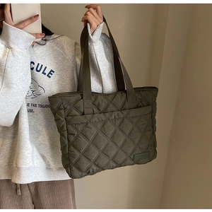 Detail of army green quilted tote bag featuring diamond stitching and wide fabric handle