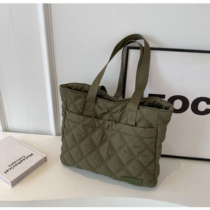 Detail of army green quilted nylon tote bag with rhombus pattern in a minimalist setting