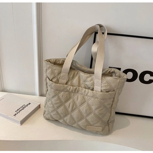 Detail of beige quilted nylon tote bag with fashion tag and wide shoulder strap