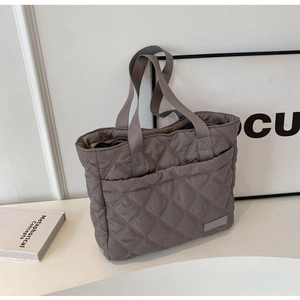 Close-up of a grey quilted nylon tote bag featuring classic diamond stitching and side label