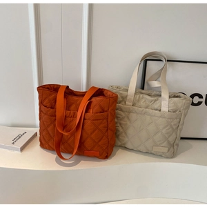 Detail of quilted tote bags in caramel and grey with diamond stitch and wide strap