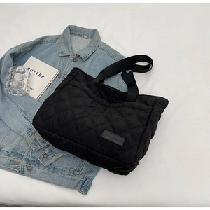 Detail of black quilted crossbody bag showing rhombus patterns and fashion label