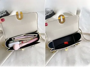 Detail view of the interior storage and golden oval lock of the cream leather handbag