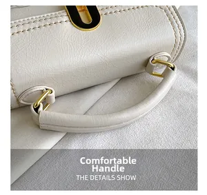 Detailed close-up of white embossed leather handbag featuring sturdy handle and gold buckle