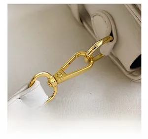 Detail view of the premium golden hardware lobster clasp on white embossed leather bag