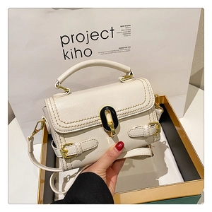 Detail of stone-patterned handbag with golden buckle and adjustable crossbody strap
