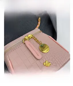 Detail view of smooth golden zipper and pink crocodile texture on the bucket bag