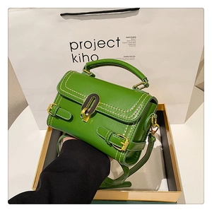 Green embossed leather handbag with gold twist lock presented in a luxury gift box