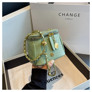 Detail of mint green crocodile embossed mini bag with gold chain in a gift box