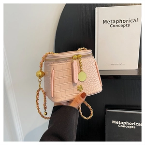 Detail of pink crocodile embossed mini box bag with golden camellia and chain strap