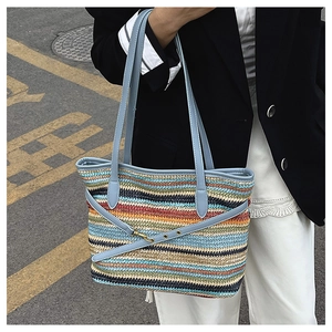 Close-up of colorful striped woven tote with blue leather straps and gold hardware detail