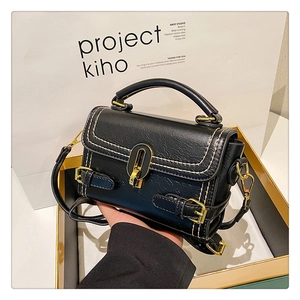 Detail of black faux leather handbag with contrast stitching and golden metal U-lock buckle