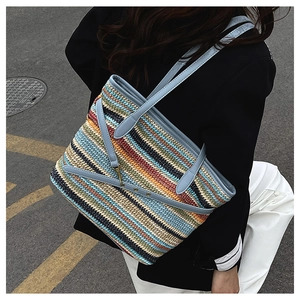 Detail of colorful woven straw tote with blue leather straps and gold buckle trim