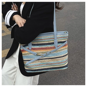 Detail of colorful woven straw tote with light blue faux leather straps and metal buckles