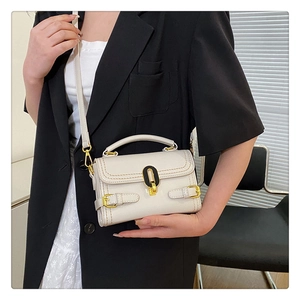 Chic off-white faux leather crossbody bag with gold buckle on model in modern blazer