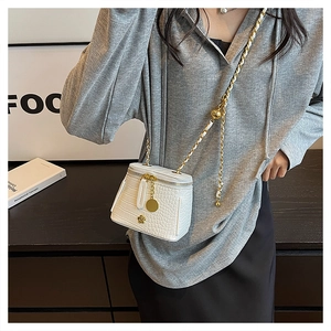 Detail of white crocodile embossed mini bucket bag with gold chain and floral metal hardware